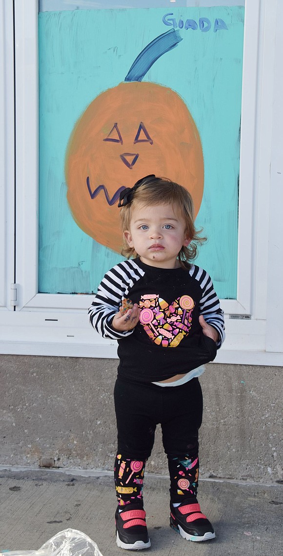 West Glen Avenue resident Giada Lio, 1, stands in front of her signed pumpkin masterpiece, which her mother Sara Morabito helped create. 