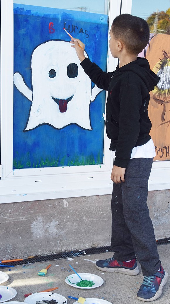 King Street School first-grader Lucas Molleturo, 7, writes “Boo” above the ghost he painted to make it extra scary.