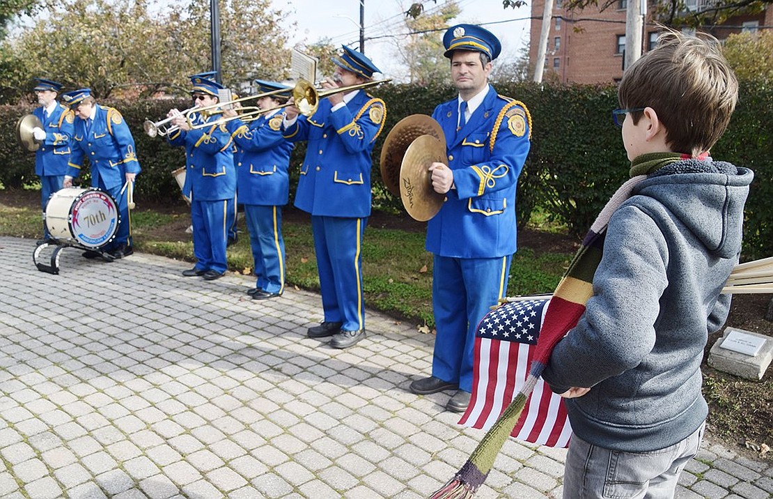 Eleven-year-old Lucas Baptista of White Plains, carrying American flags he passed out to ceremony attendees, watches as the Port Chester American Legion Band plays a patriotic number. He is the son of band member Renato Baptista, playing the cymbals.