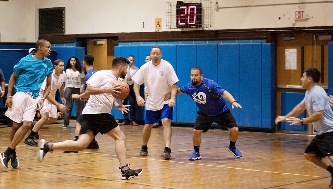 Police Officer Andy Polanco runs with the ball toward the basket as physical education teacher Joseph Facciola attempts to block. 