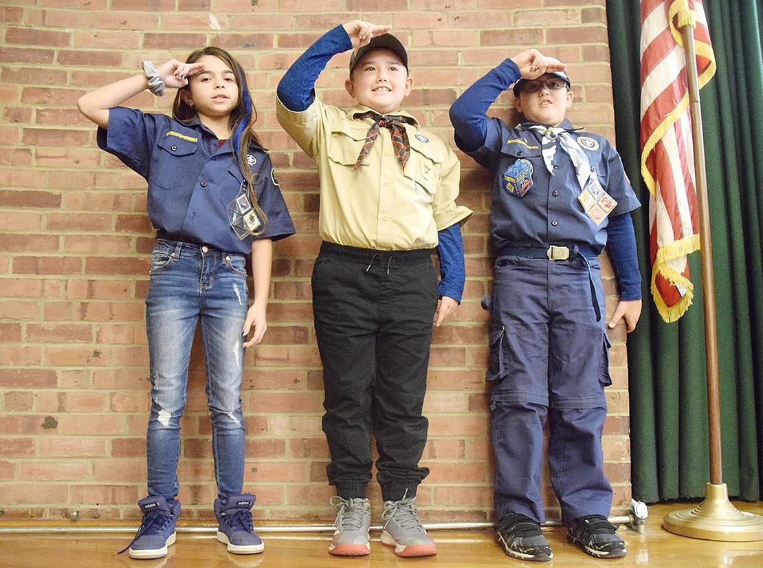 Proudly saluting, King Street School students involved with the Boy Scouts of America kick off the ceremony by leading the crowded auditorium in the Pledge of Allegiance. From the left: fourth-grader Sophia Faraci, fourth-grader Evin Eski and third-grader Santo Giordano.