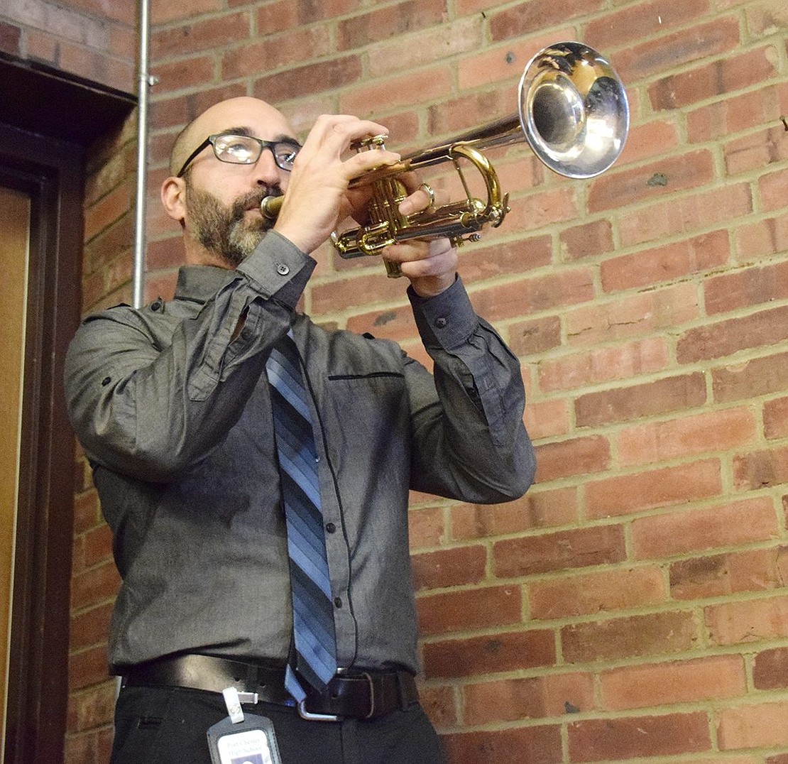 As the audience stands in honor of the soldiers, Port Chester High School Band Director Mike Miceli plays a patriotic tune on the trumpet.