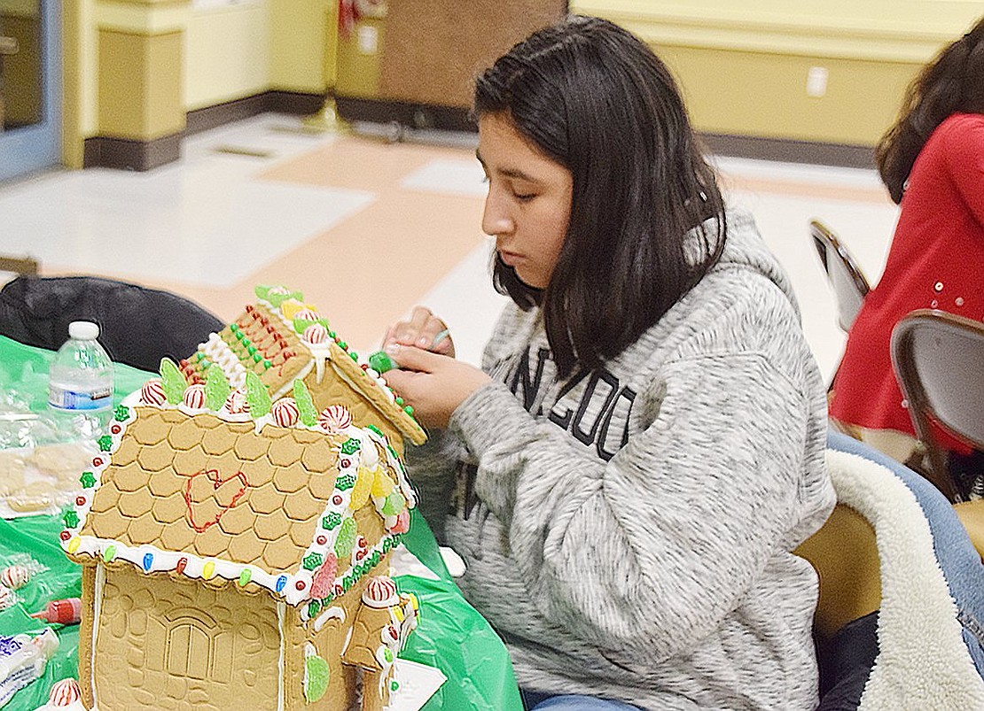 Port Chester Middle School sixth-grader Desiree Marquez, 11, precisely designs loops of green frosting on the roof of her gingerbread house.
