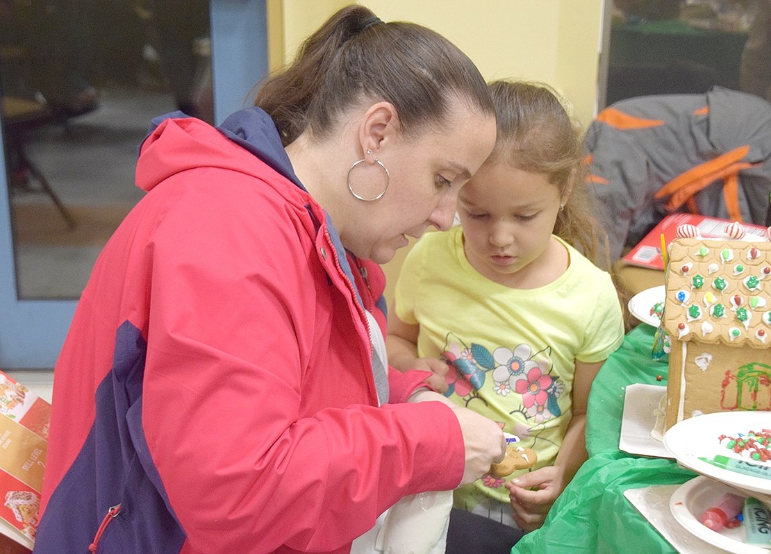 Haines Boulevard residents Kelly Castro and her daughter Sophia, 4, carefully decorate a gingerbread man with frosting as part of their holiday creation.