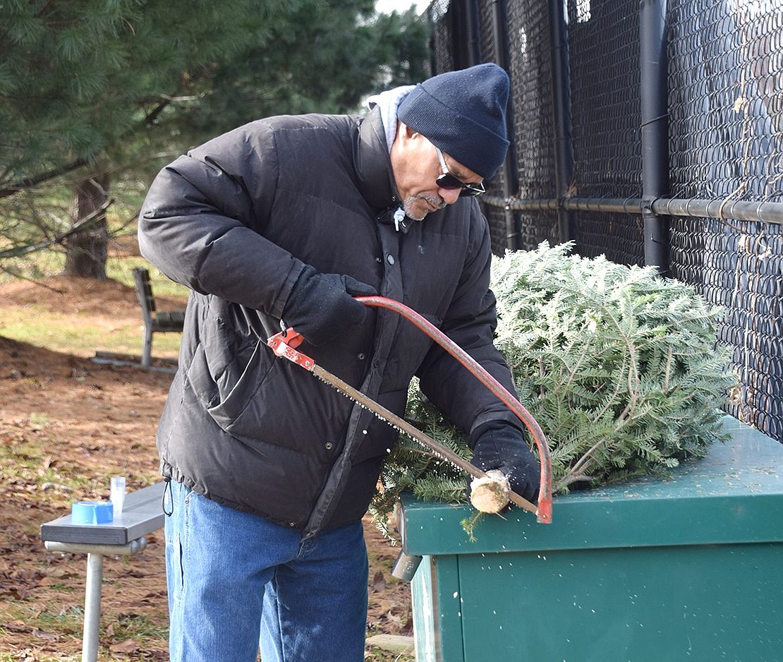 Port Chester High School Marching Band parent volunteer Mike Davis prepares a Christmas tree for its new home by cutting off the end of its trunk during the band’s annual Christmas Tree Sale on Sunday, Dec. 8. Throughout the weekend, the band sold roughly 70 trees for $70 each to benefit the Pride of Port Chester.