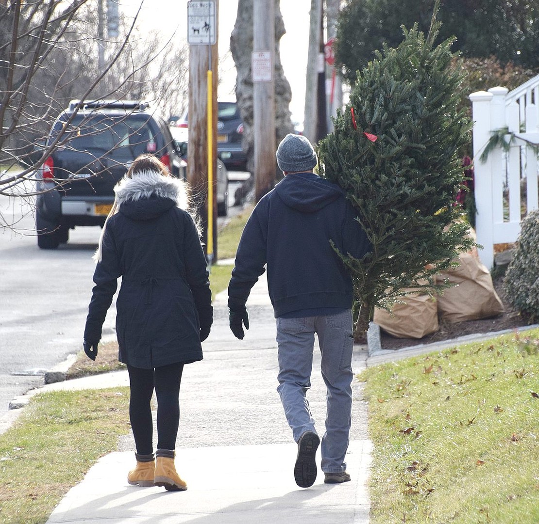 After finding the perfect Christmas tree, Robert Maxwell carries his new decorative holiday plant off to his home on Wesley Avenue with his daughter Lia, a Port Chester High School junior.