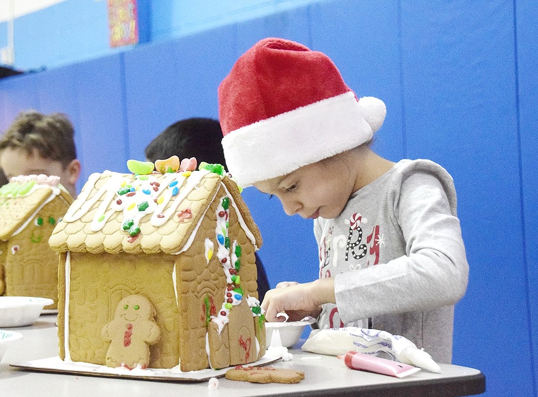 With her head warmed by a Santa hat to showcase the holiday spirit, Kate Plateroti forages through a bowl of assorted candies to put the perfect finishing touches on her gingerbread house. The kindergartener is one of 100 King Street Elementary School students building cookie homes during a PTA-sponsored craft event on Friday, Dec. 6.
