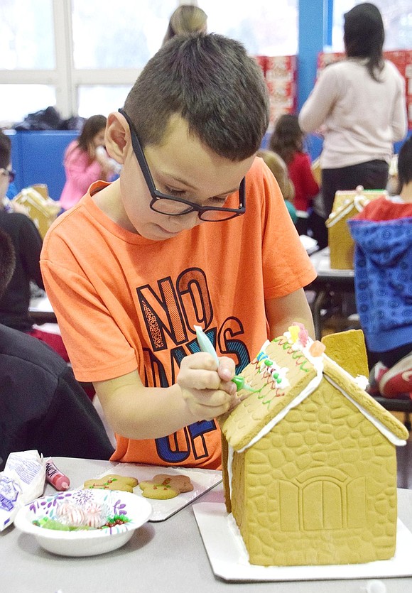 Pursing his lips in concentration, fourth-grader Justin Garcia paints the shingles of his gingerbread house a festive green.