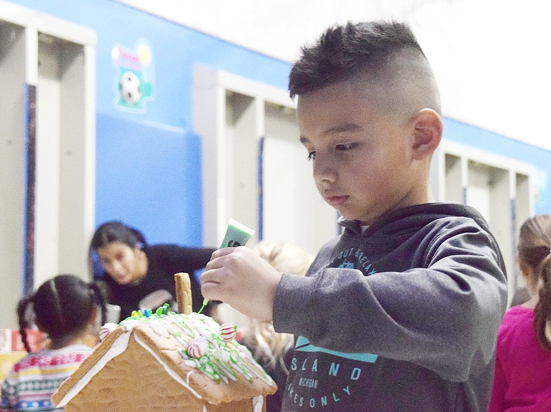 Is snow green? In second-grader Jared Bautista’s world it is, so he makes sure to drizzle plenty of lime-green, edible gel on the roof of his gingerbread house.