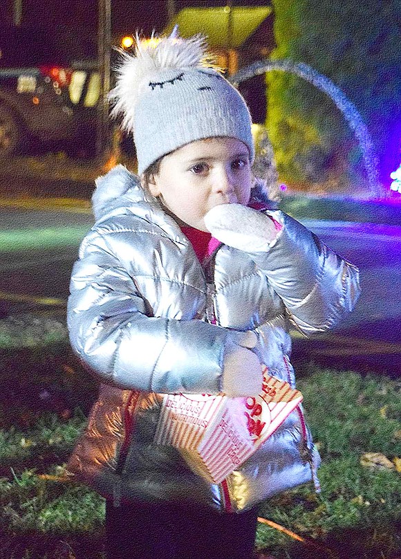 Bundled up and clutching a box of popcorn, Hillandale Road 3-year-old Riley Brauntuch warms up with a salty snack.
