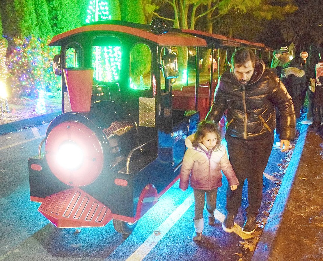 Rye Brook residents Gloria Waisburg, 3, and her uncle Adrian scurry off the polar express train after taking a fun ride around Pine Ridge Park.