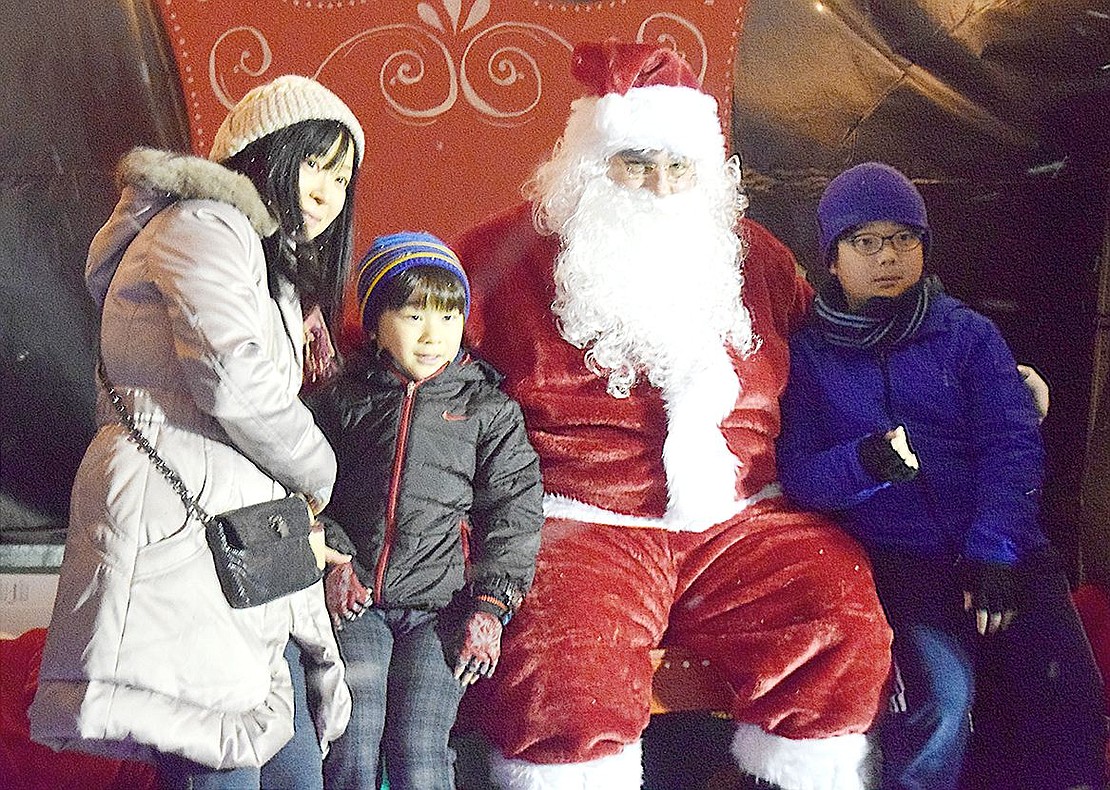 After Ridge Street School fifth-grader Atsuhiro Wada (right) and his second-grade brother Hiroyoshi take a picture with Santa Claus, their mother Kyoko jumps in for a family photo. The family lives on Berkley Drive.