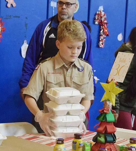 Volunteering for the morning, Greenwich, Conn. Troop 35 Boy Scout Grayson Brehm, 11, places containers filled with bagels, eggs and other breakfast items on a table for guests to enjoy.