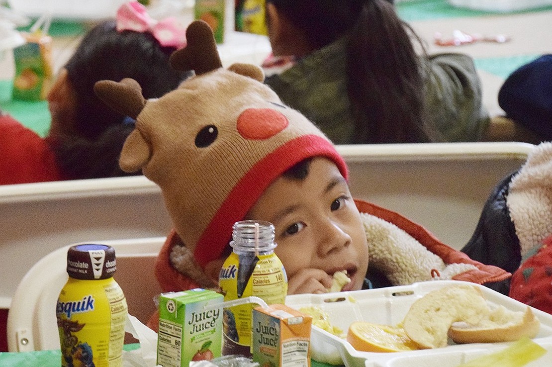 Dressed in appropriate Christmas attire, South Ridge Street resident Julian Sanchez, 6, enjoys his breakfast while waiting for Santa to arrive.