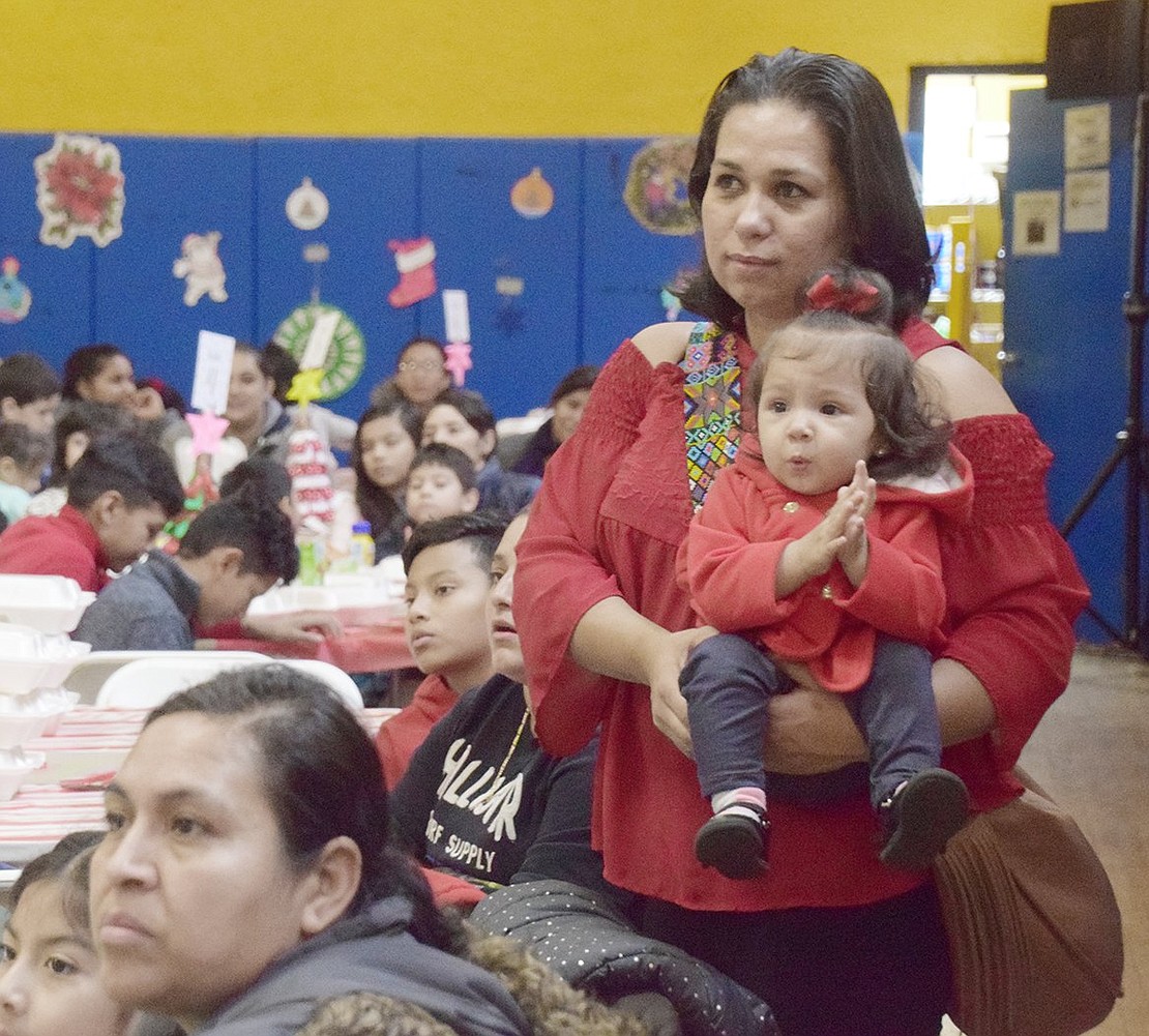 Washington Street resident Maria Hernandez holds her excited 1-year-old daughter Christina as they listen to speakers.