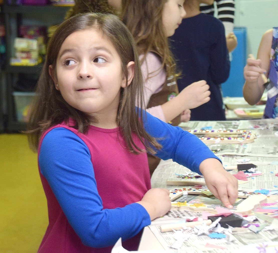 Park Avenue School kindergartener Ava Ianello looks back for a reassuring smile from her mother as she sticks colorful stars onto her picture frame.