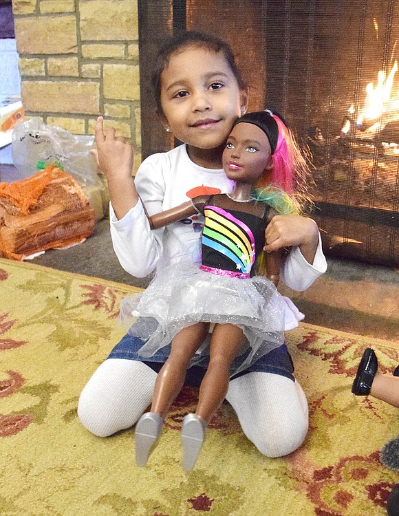 Showing off her extra-tall doll Olivia, Nella Lane 5-year-old Jacelyn Miranda grins for the camera by the Girl Scout House fireplace.