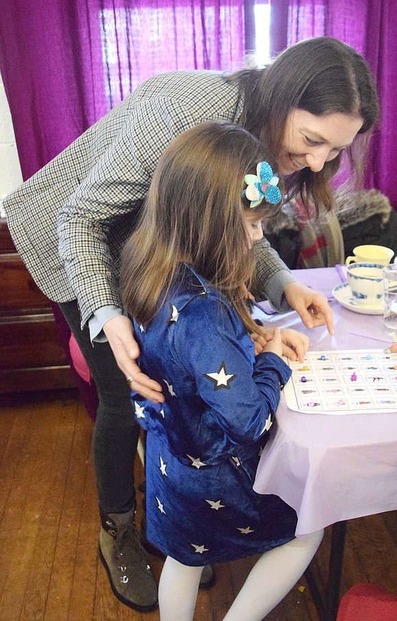 Glendale Place resident Jordan Allen leans over to giggle with her 6-year-old daughter Samantha as they place markers on a board for American Girl Doll bingo.