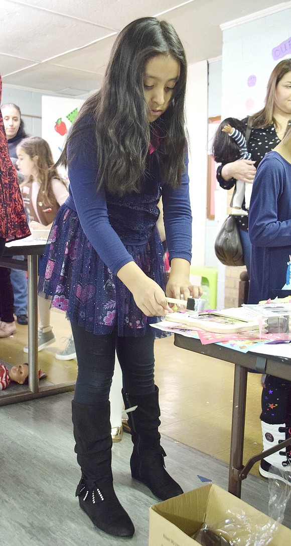 Park Avenue Elementary School third-grader Kaylee Garcia meticulously paints a picture frame in the Girl Scout House basement.