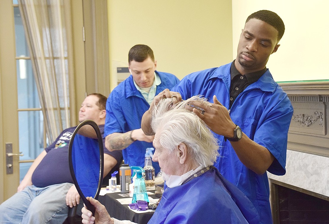 Comly Avenue resident Knute Numme watches in the mirror as Westchester Barber Academy student Richard Smiles cuts away at his hair. In honor of the Martin Luther King Jr. Day of Service, Westchester Barber Academy students gave free haircuts to veterans and seniors at the Crawford Mansion Community Center on Saturday, Jan. 18.