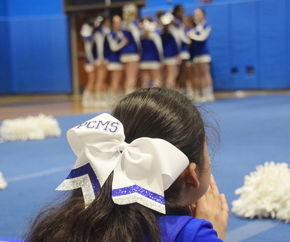 Before the varsity team takes the floor, seventh-grader and modified team member Madeline Molina looks on at the older cheerleaders in anticipation.