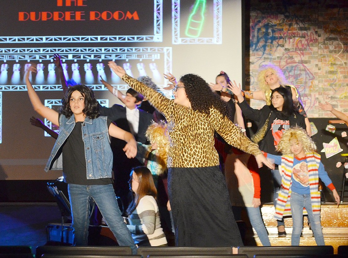 Leading a shadow of big-haired cast members, Drew Boley (played by Gage Saresky) and Justice Charlier (played by Damaris Ramirez) dance to the echoes of “Nothin’ But a Good Time.”