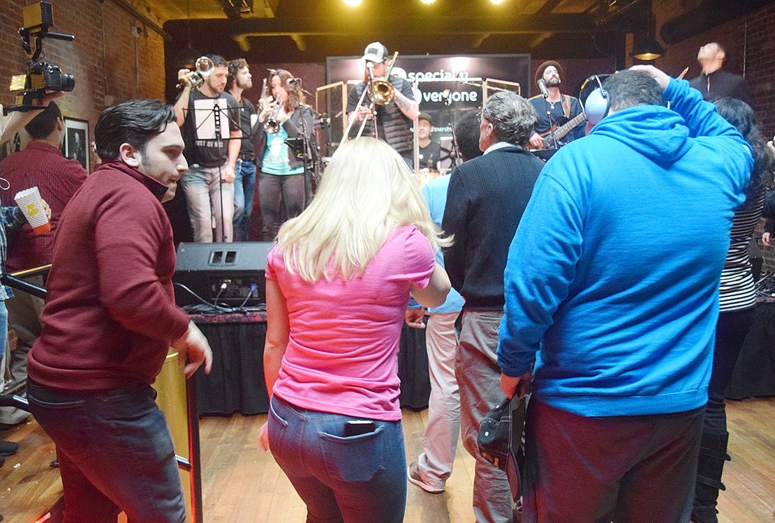 Patrons dance in front of the stage as the full Ensemble plays a loud tune.