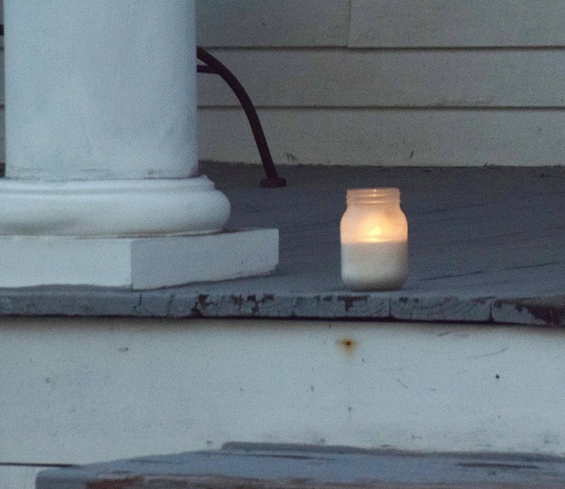 A single candle rests on the front porch of 62 Wesley Ave.