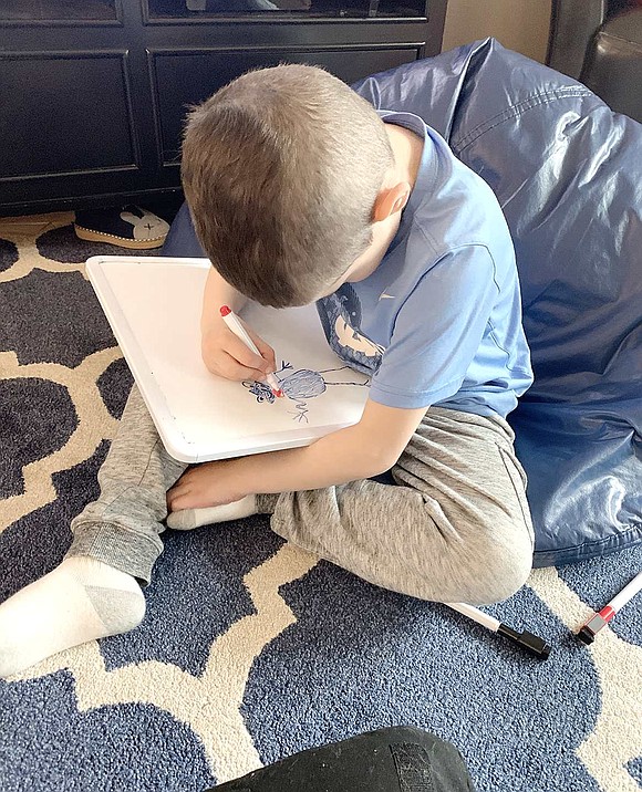 After using a blue marker to draw a frog on a white board, Ridge Street School kindergartener John Gasparini picks up the red to give him a fancy bowtie. Courtesy of Mackenzie Gasparini 