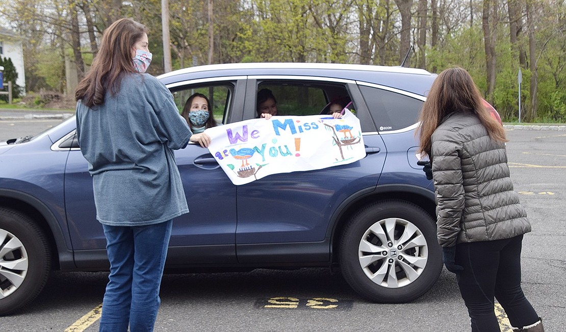 First-graders Ellie and Megan Tapper show off their creativity by displaying a banner to Ridge Street Elementary School first-grade teachers Christine Rickard (left) and Michelle Forzaglia. First-grade parents took part in a parade on Wednesday, Apr. 29, as they drove by their children’s educators, who waved and spoke to them from the school’s lower parking lot.