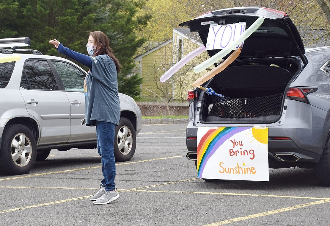 First-grade teacher Christine Rickard waves to a student as they drive through the lower parking lot of Ridge Street Elementary School.