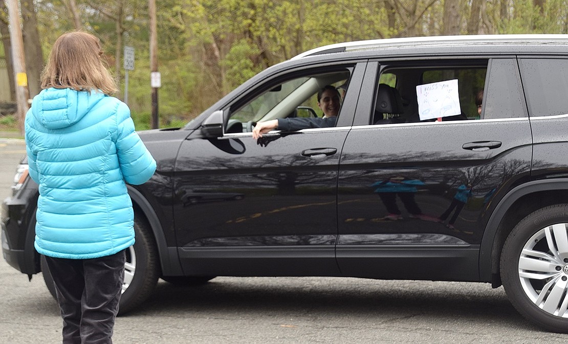 Michael O’Neill Jr. holds up a sign from his car that reads ‘I miss you’ for his teacher Karen Tagliaferri.