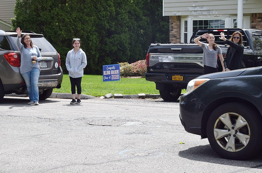 Betsy Brown Road residents Jackie (left) and Ella Piacente, an eighth-grader, and Country Ridge Drive residents Kelly and Alex Beatty, also an eighth-grader, wave to the oncoming teachers and administrators.