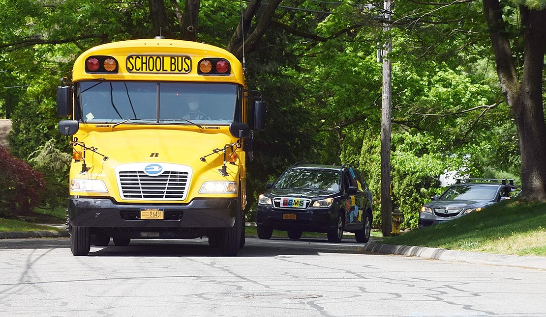 A bright yellow school bus leads the Blind Brook Middle School parade down Country Ridge Drive.