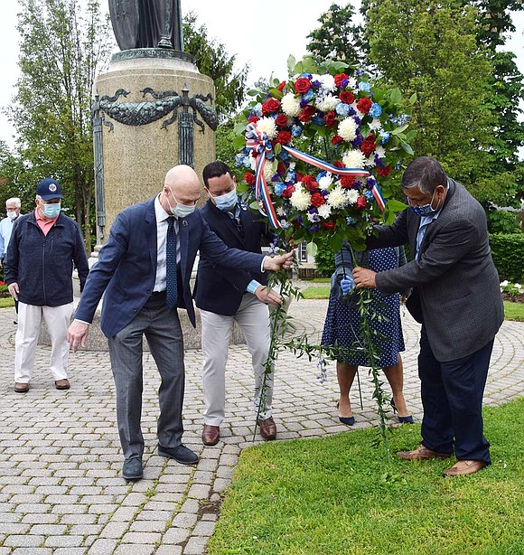 Port Chester Trustees Frank Ferrara, Alex Payan, Joan Grangenois-Thomas (hidden) and Luis Marino place a memorial wreath in the park.