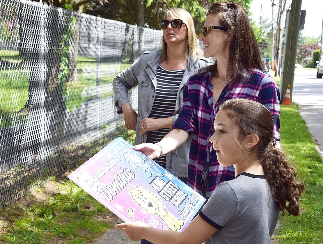 King Street School third-grader Juliet Petriella hands a sign to Jill Geller as they contemplate how to arrange them on the fence.