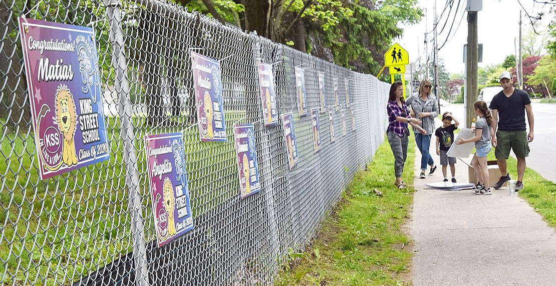 PTA officers and a few of their children hang a customized sign for each of the 63 King Street School fifth-graders graduating at the end of the year.