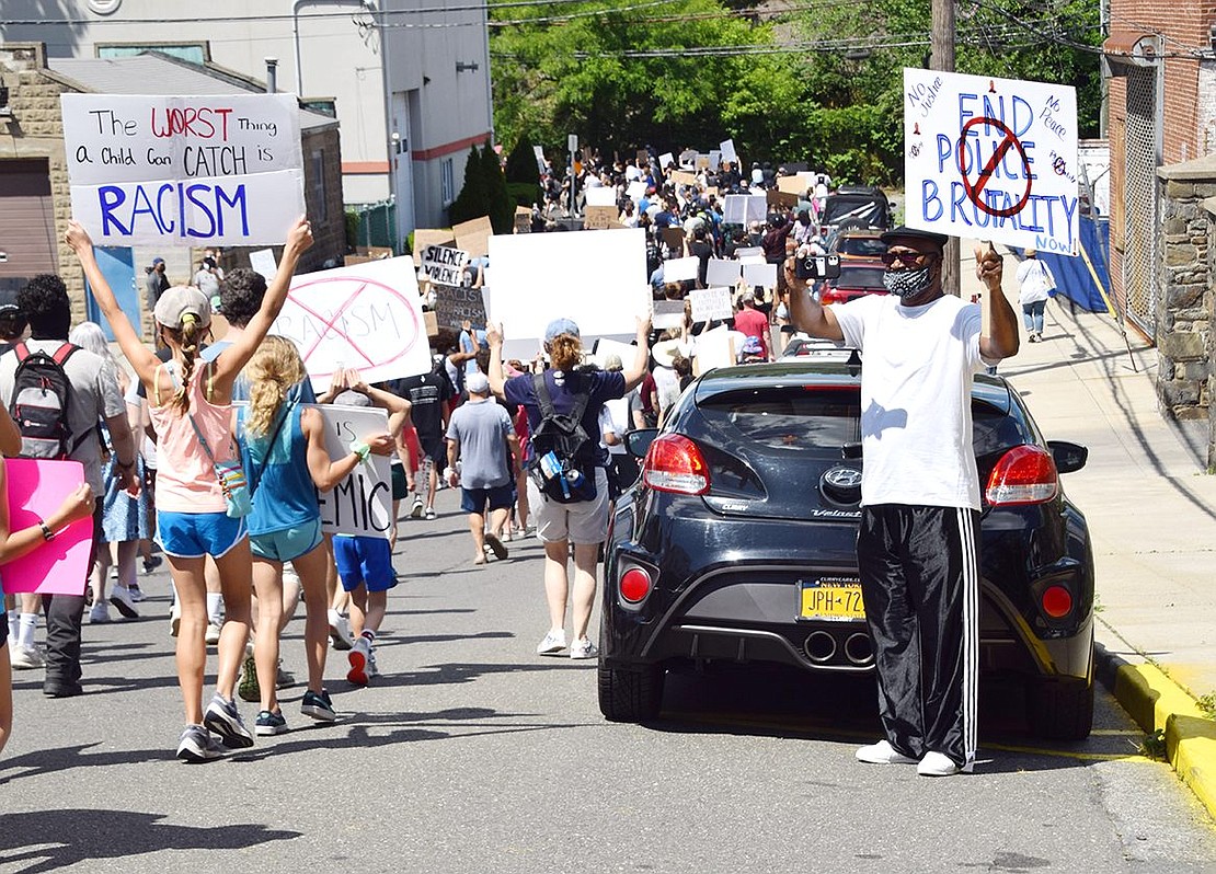 As he holds a poster calling for an end to police brutality on Sunday, June 7, Port Chester native Michael Williams records hundreds of protesters at the Black Lives Matter rally passing by as they march down Ryan Avenue.