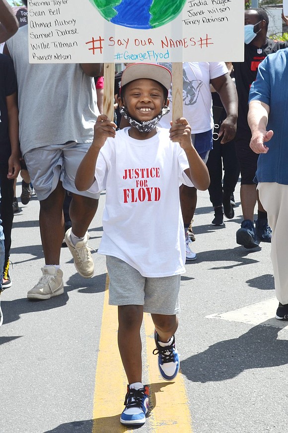 Nine-year-old White Plains resident Ashton Nichols smiles as he walks at the front of the protest while carrying a sign listing some of the names of those who have been killed due to police brutality.