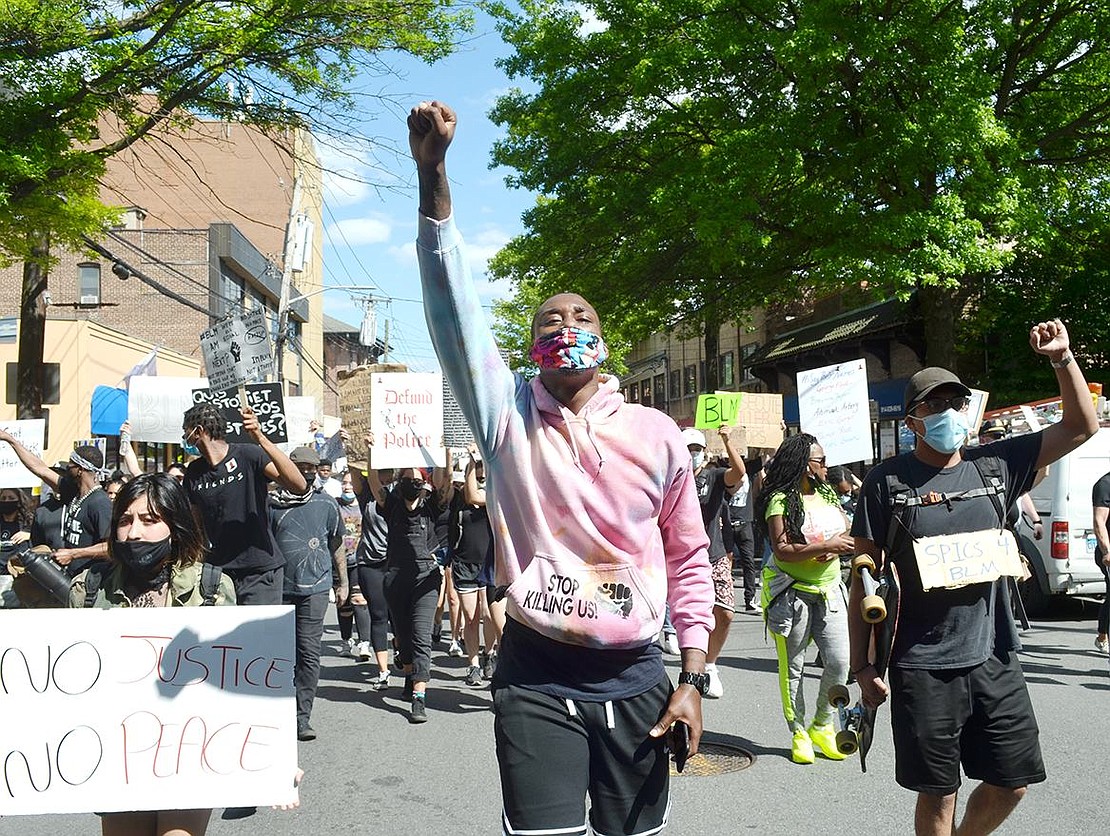 University Place resident Jason Foust holds up a fist in solidarity as he marches up Westchester Avenue.