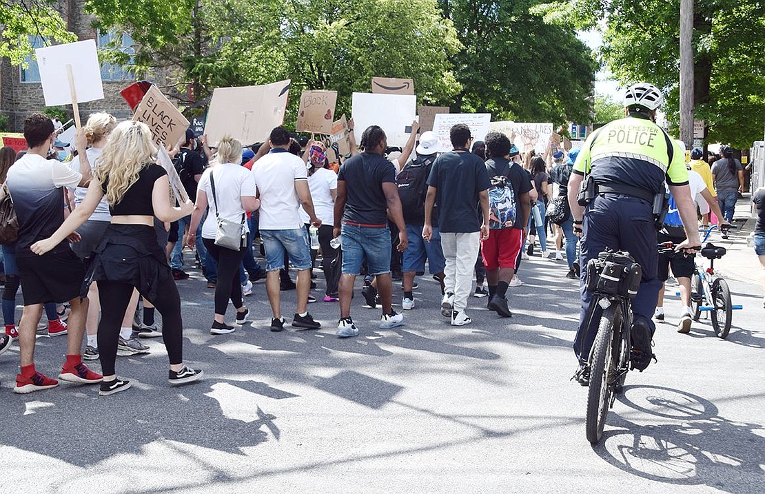 A Port Chester police officer rides his bike alongside peaceful protesters as they make their way down Westchester Avenue.