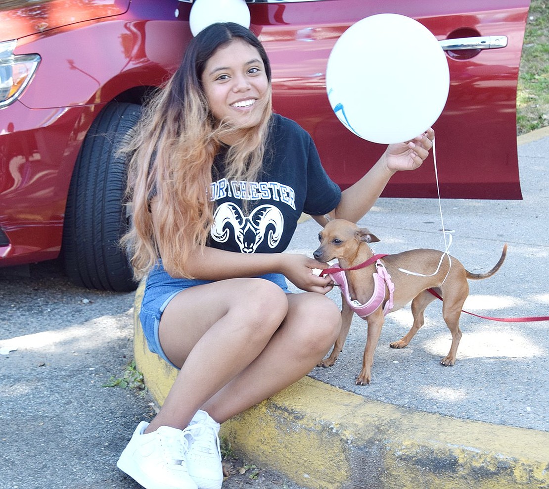 Senior Ana Flores feels love from the entire family, including her dog Annie who shows support before the parade by visiting for quick cuddles with a balloon.