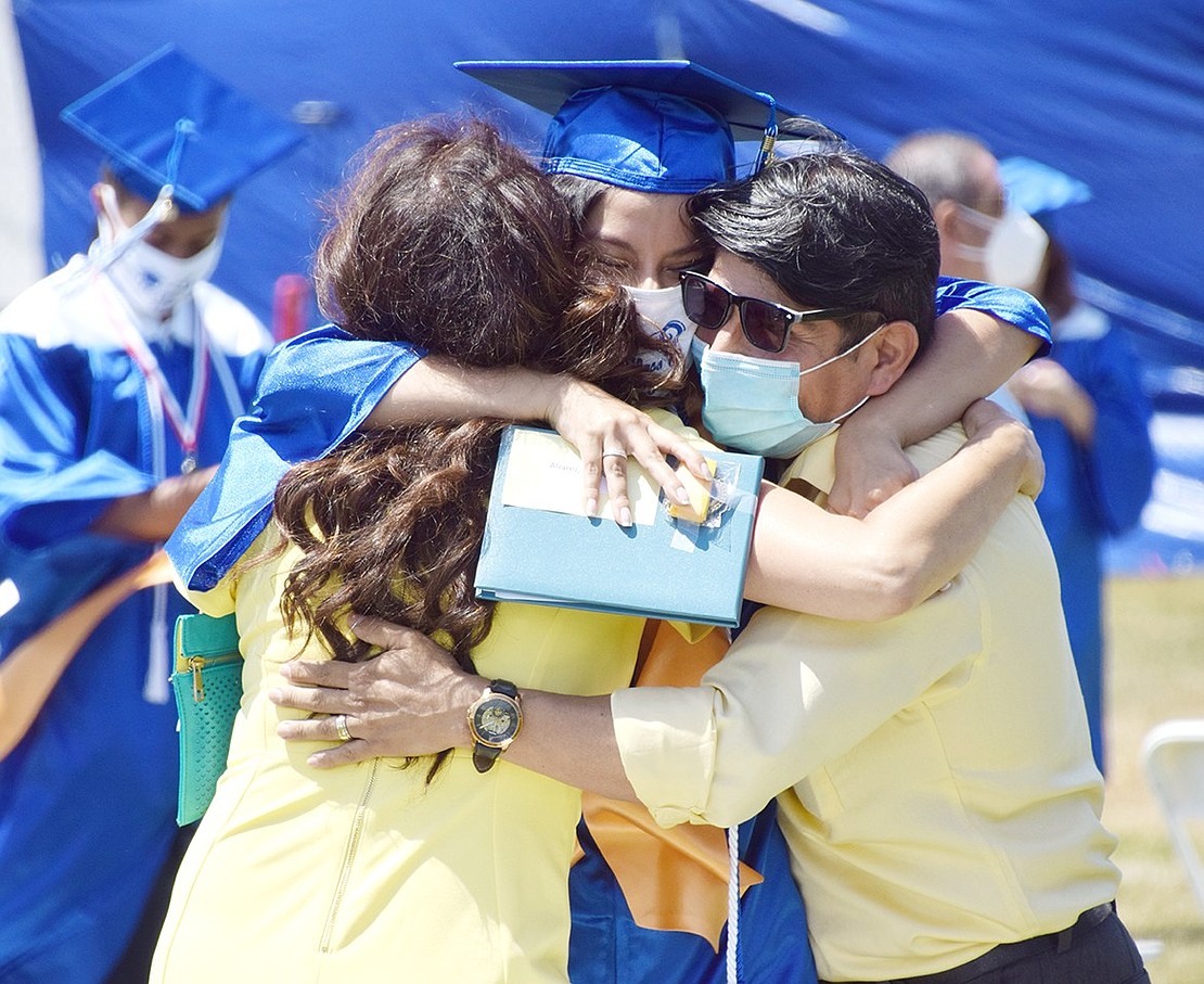 When her Port Chester High School Class of 2020 graduation ceremony ends on Friday, June 26, Penelope Alvarez grabs her parents and embraces them. In an historic year due to COVID-19, nine different ceremonies were held, and students were able to graduate next to their parents on the high school baseball field.