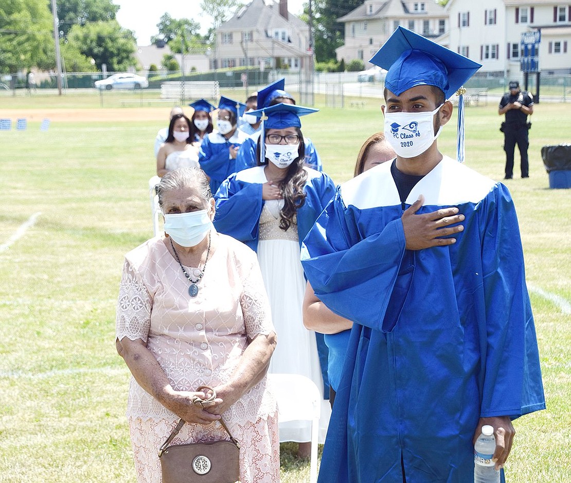 Cristian Cano places his hand on his heart as pre-recorded Class of 2020 graduates sing the national anthem.