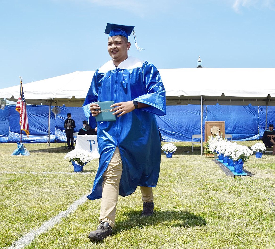 After picking up his diploma from the dais, Carlos Ortega proudly strides back to his seat to celebrate with his family.