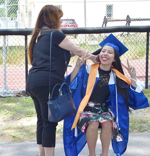 Moments before heading into her ceremony, Bryanna Noriega makes silly faces at her friends while her mother Sandra fixes her hair in the preparation area on the Neuton Avenue basketball courts.