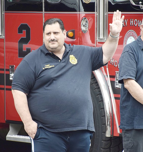 Port Chester Fire Chief Ricky Casterella waves at the loud celebratory car parade as it makes its way down Westchester Avenue.
