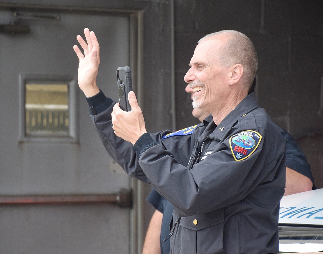 Port Chester-Rye-Rye Brook EMS Director Scott Moore is all smiles as he records the caravan driving by the Ellendale Avenue headquarters.