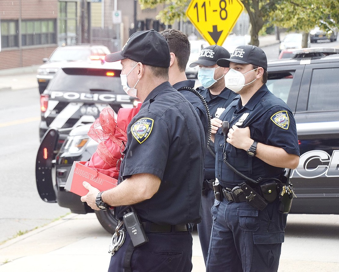 Port Chester Police Lieutenant Steve Barbara holds onto a gift the department received for their service as the car parade drives by.