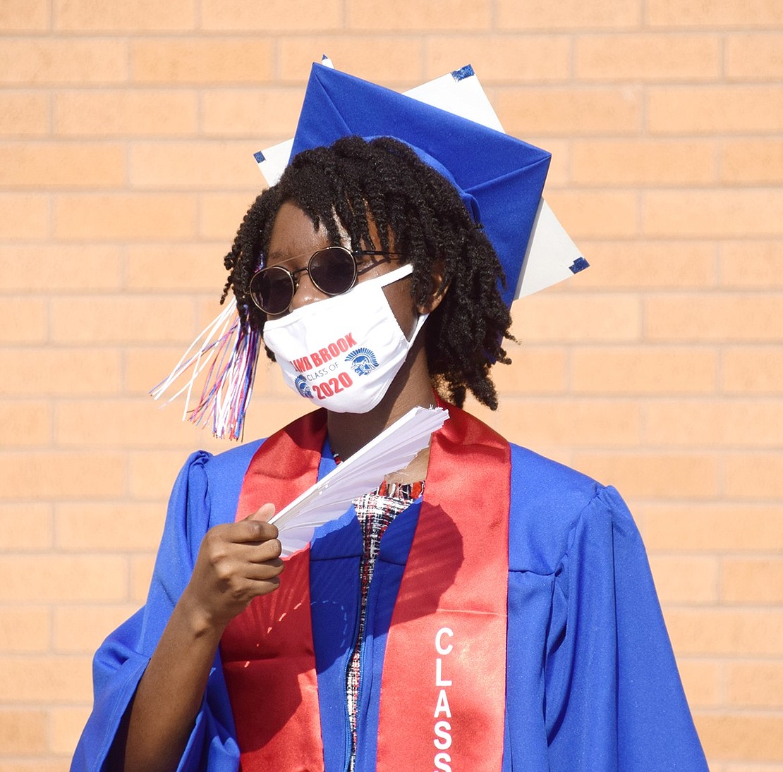 Though students are gathering just before 9 a.m., it’s already hot. To beat the heat, Alexandra Dennis whips out a fan to create her own breeze.